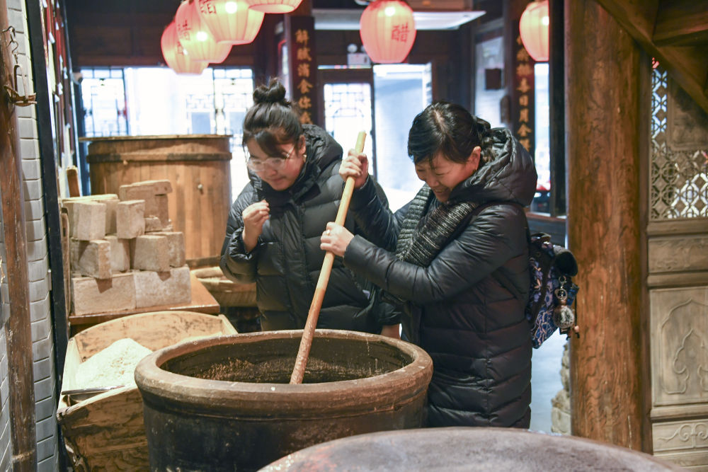 游客在平遙古城東湖老醋坊內體驗陳醋發酵打耙（2022年1月28日攝）。新華社發（梁生仁攝）