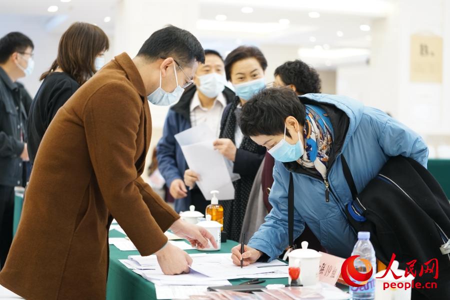 3月2日，在北京會議中心駐地，前來報到的全國政協委員在工作人員的引導下簽到、領取證件和會議資料。人民網記者 王天樂攝